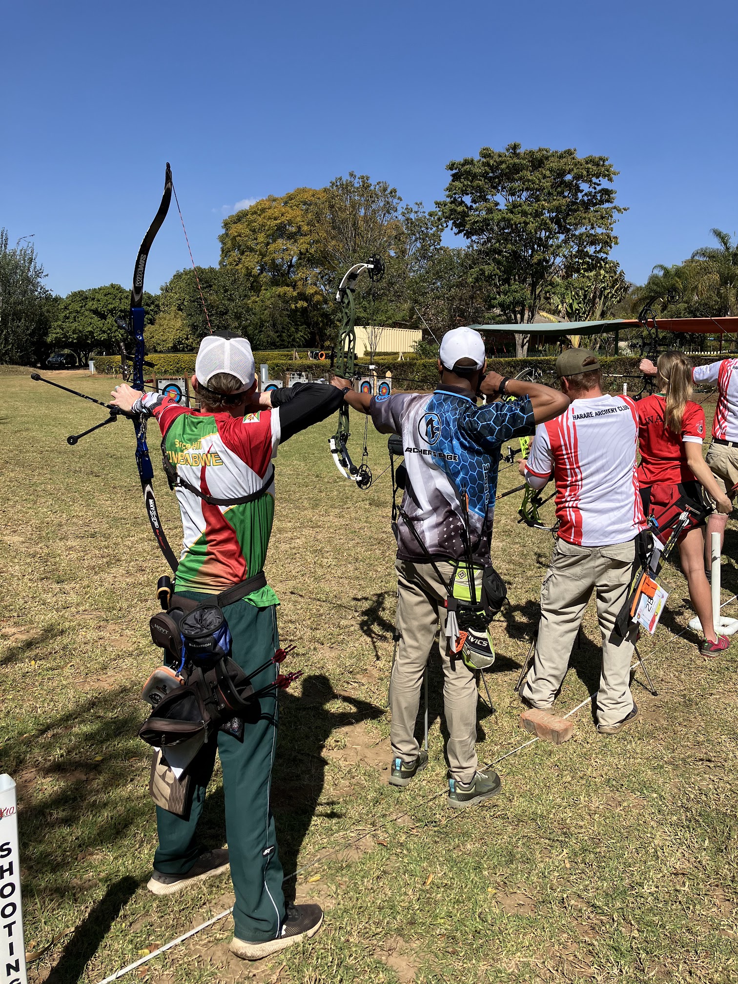 Four archers at full draw, aiming away from the viewer